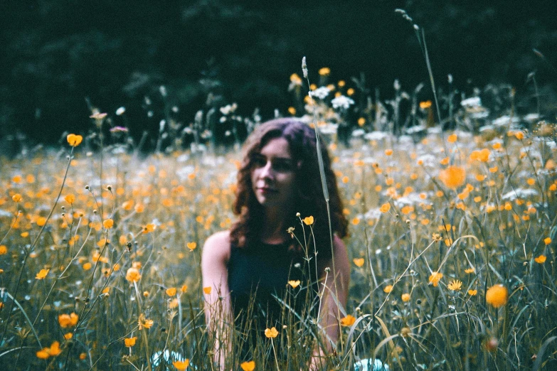 a beautiful woman standing in a field of flowers