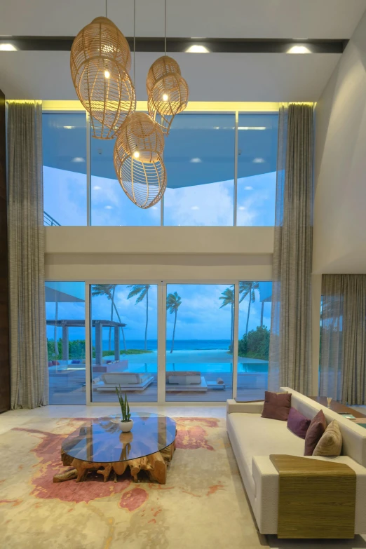 a living room with large windows, beige couches and a wooden coffee table