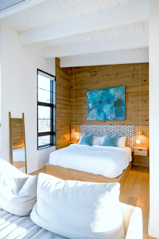 a white bed in a wooden room with a painting on the wall