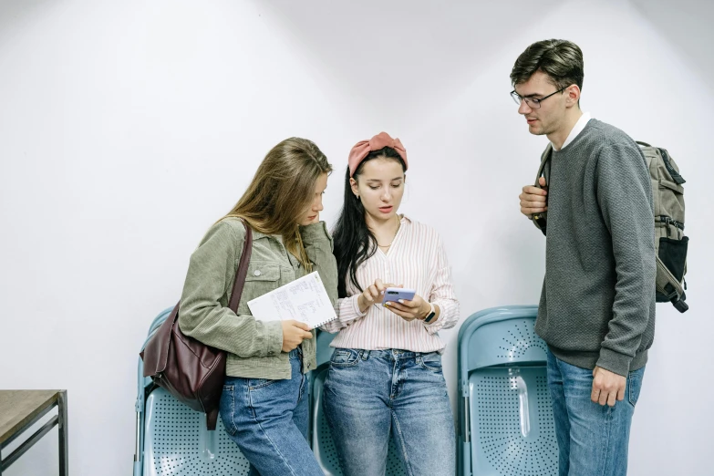 three people standing around in front of a wall with electronic devices