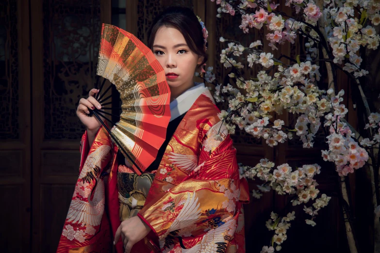 a woman with a oriental fan in front of flowers