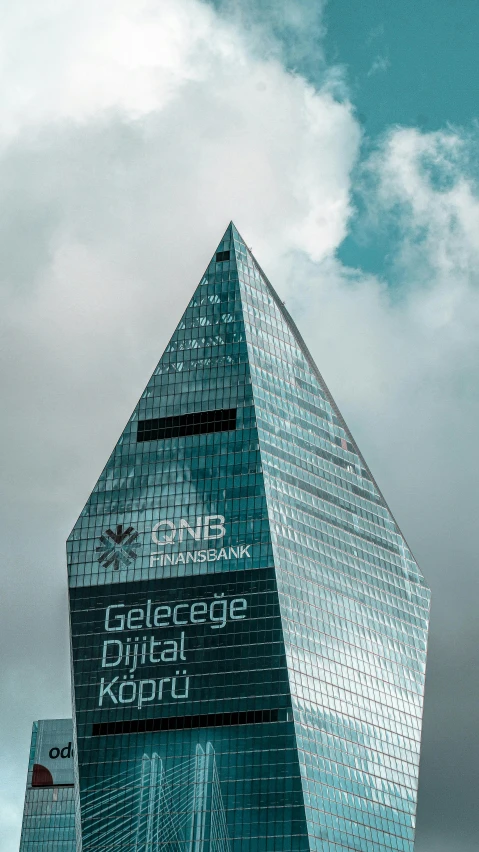 a very large glass building under a cloudy sky