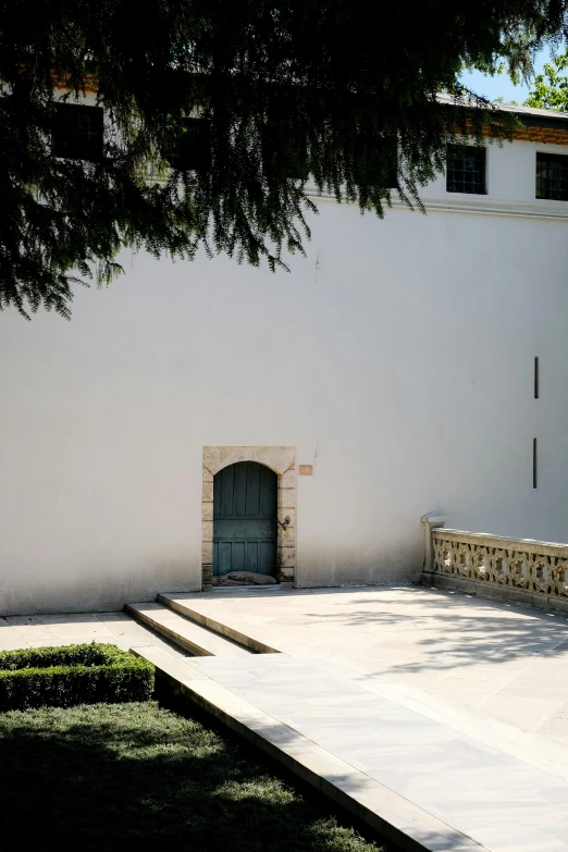 an empty courtyard sits beneath a tree near a wall