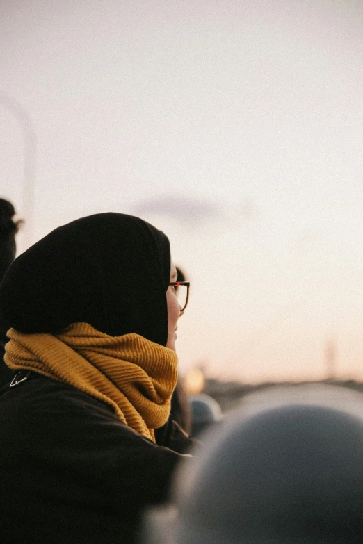 a woman wearing a scarf looking out at the sky