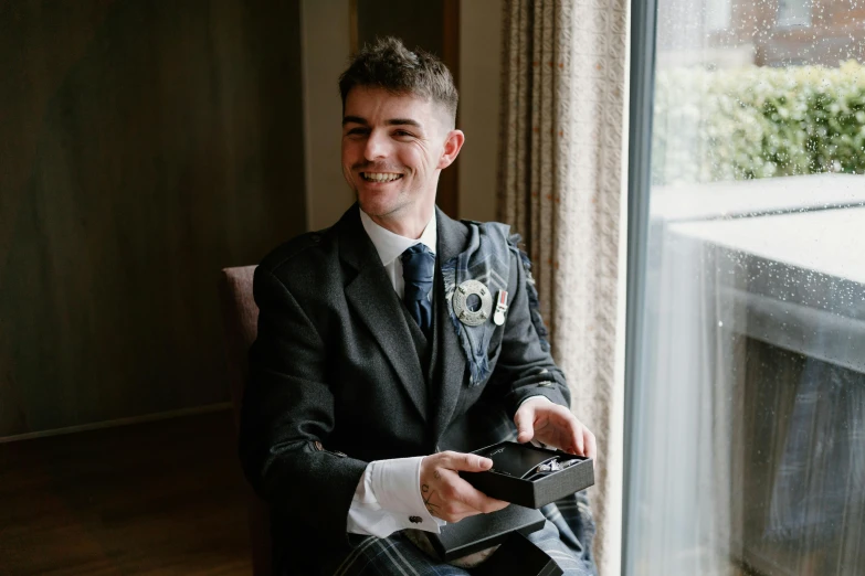 a man in a suit holds an object near a window