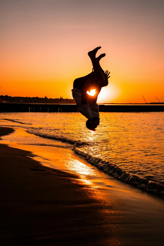 a man jumps into the air over the beach