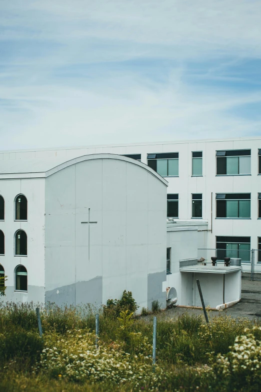 a white building sits on the edge of a grassy area