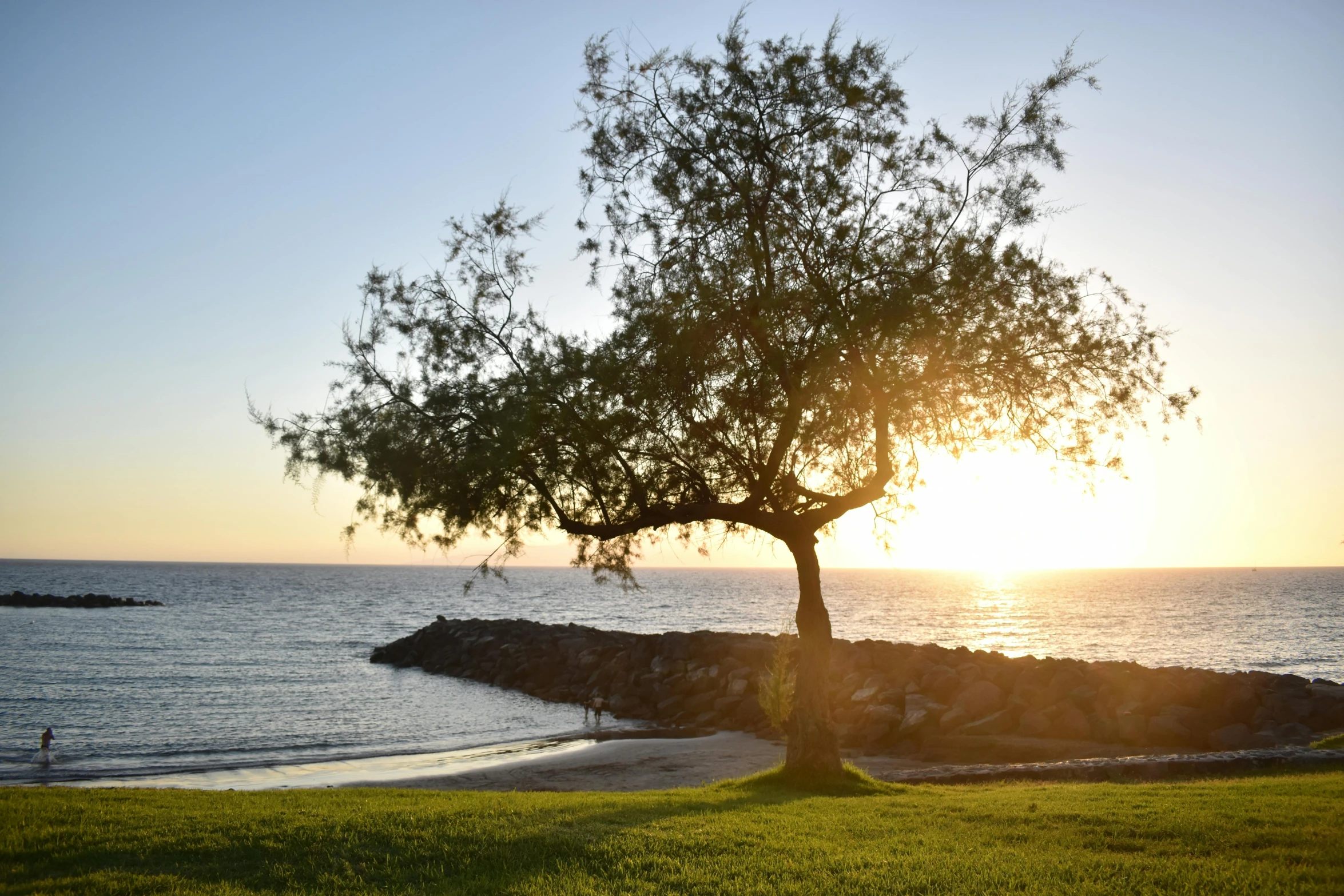 the sun is setting on a rocky shore