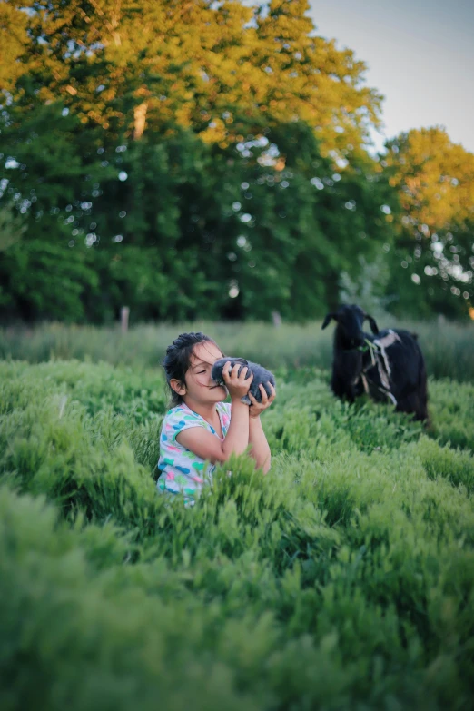 a little girl sitting in the grass with her dog