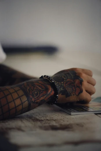 arm with tattoos on a person holding a piece of paper
