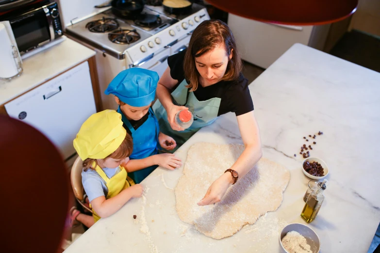 a lady and children are preparing food in the kitchen