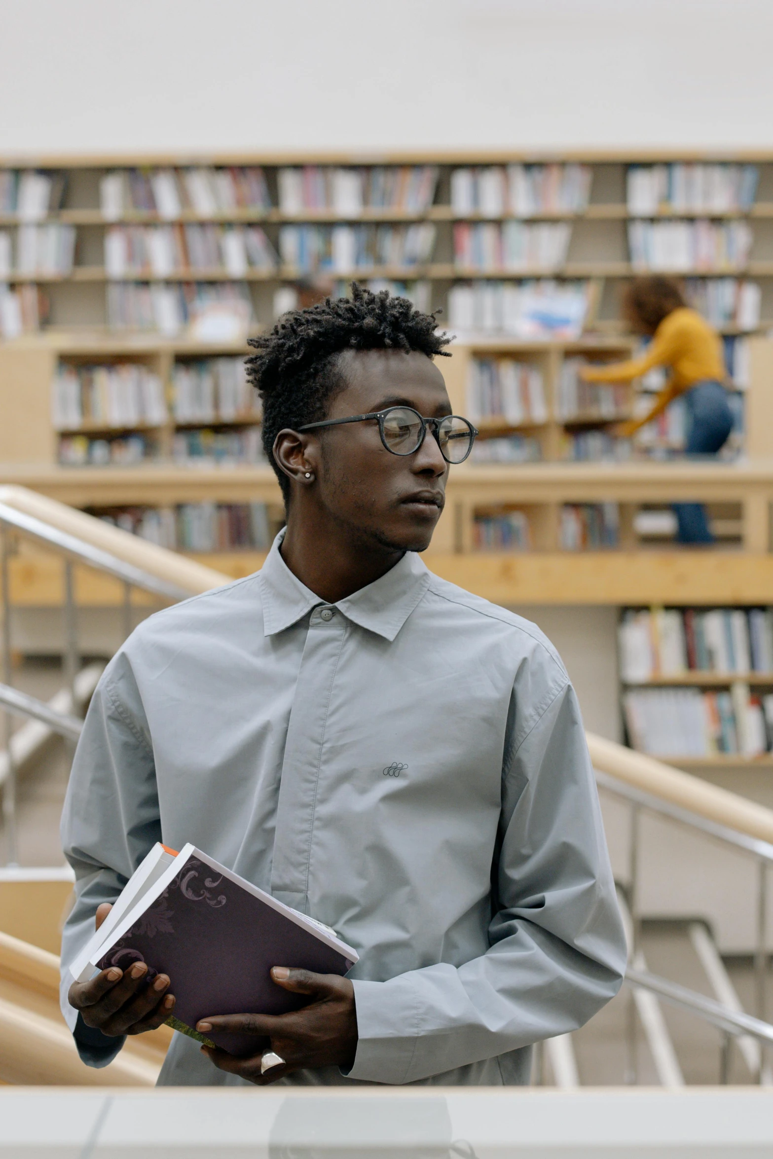 the man is reading in front of bookshelves