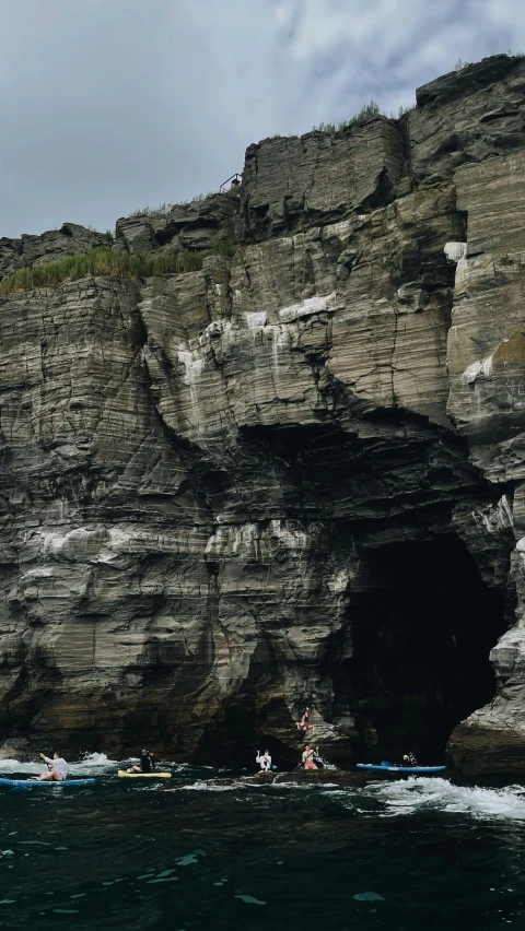 people kayaking through water towards a cave