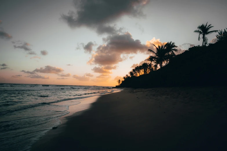 a beach that has the sun setting on it