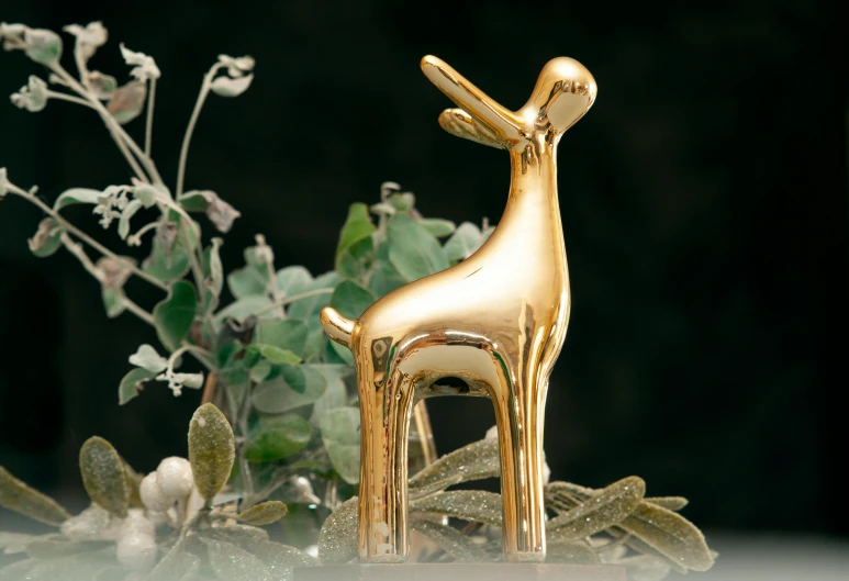 golden giraffe sculpture standing in front of plants