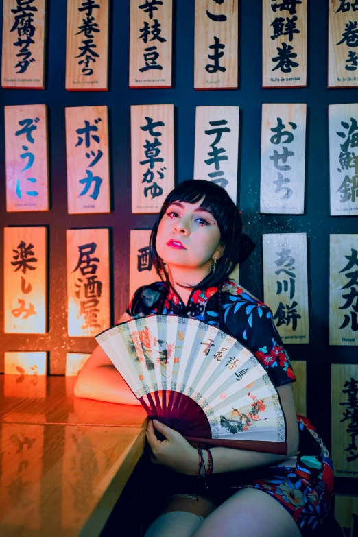 a woman in oriental clothing holds a fan near a table