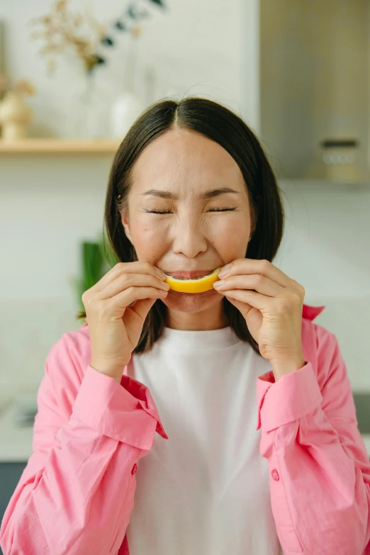 a woman holds a fruit in her mouth and laughs