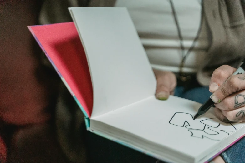 a woman with tattoos holding a notebook and writing