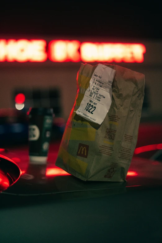 a paper bag and a soda can are sitting on a car's windshield