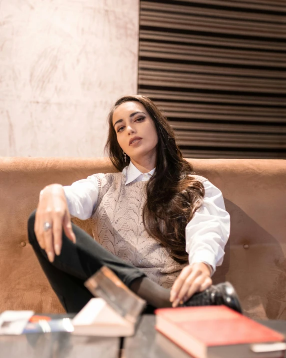 a woman in a sweater sitting on top of a brown couch