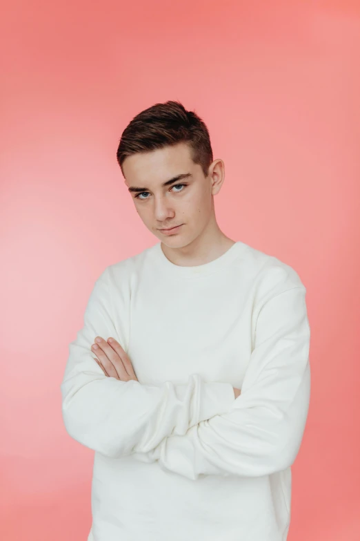 young man with arms crossed and a sweater over his shoulders