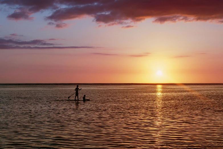 the sun sets over water and is shining behind the horizon