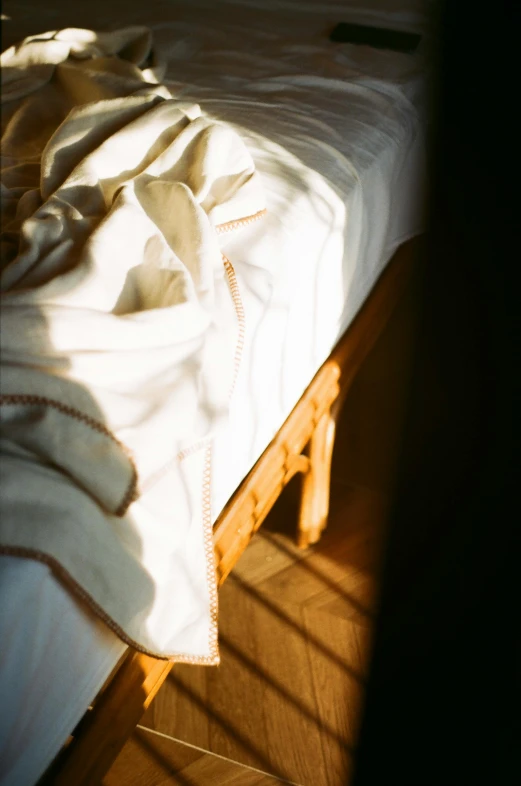 an unmade bed with white sheets in the morning sun