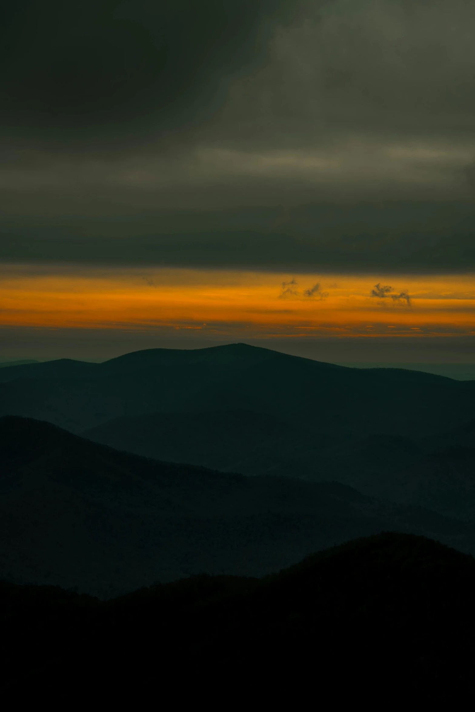 a dark view of mountains under a cloudy sky