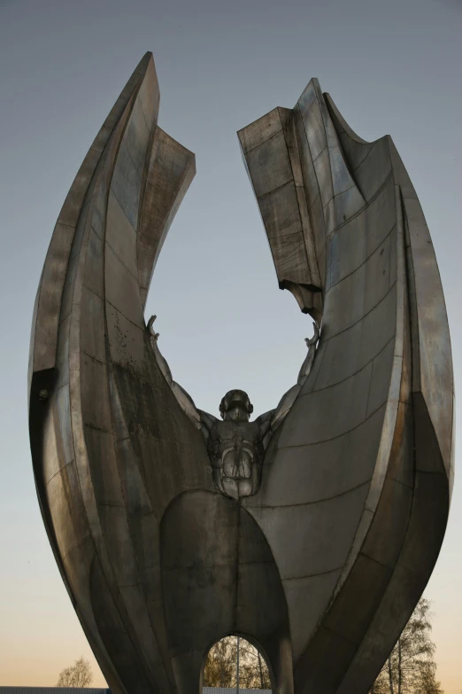 a statue of a man on a ledge in front of an enormous object