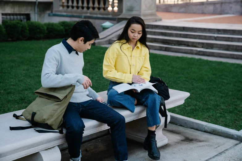 a couple of people sitting on a cement bench