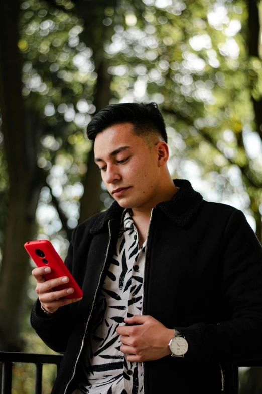 a young man checks his phone while sitting outside