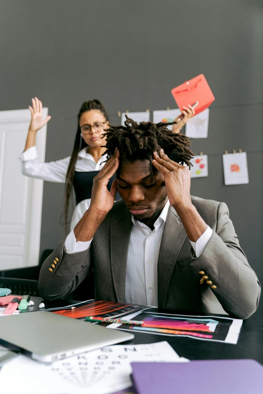 a man in a suit is holding his head while working on a computer