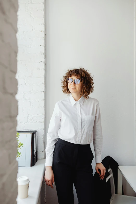 woman posing next to a table wearing a white shirt and black pants