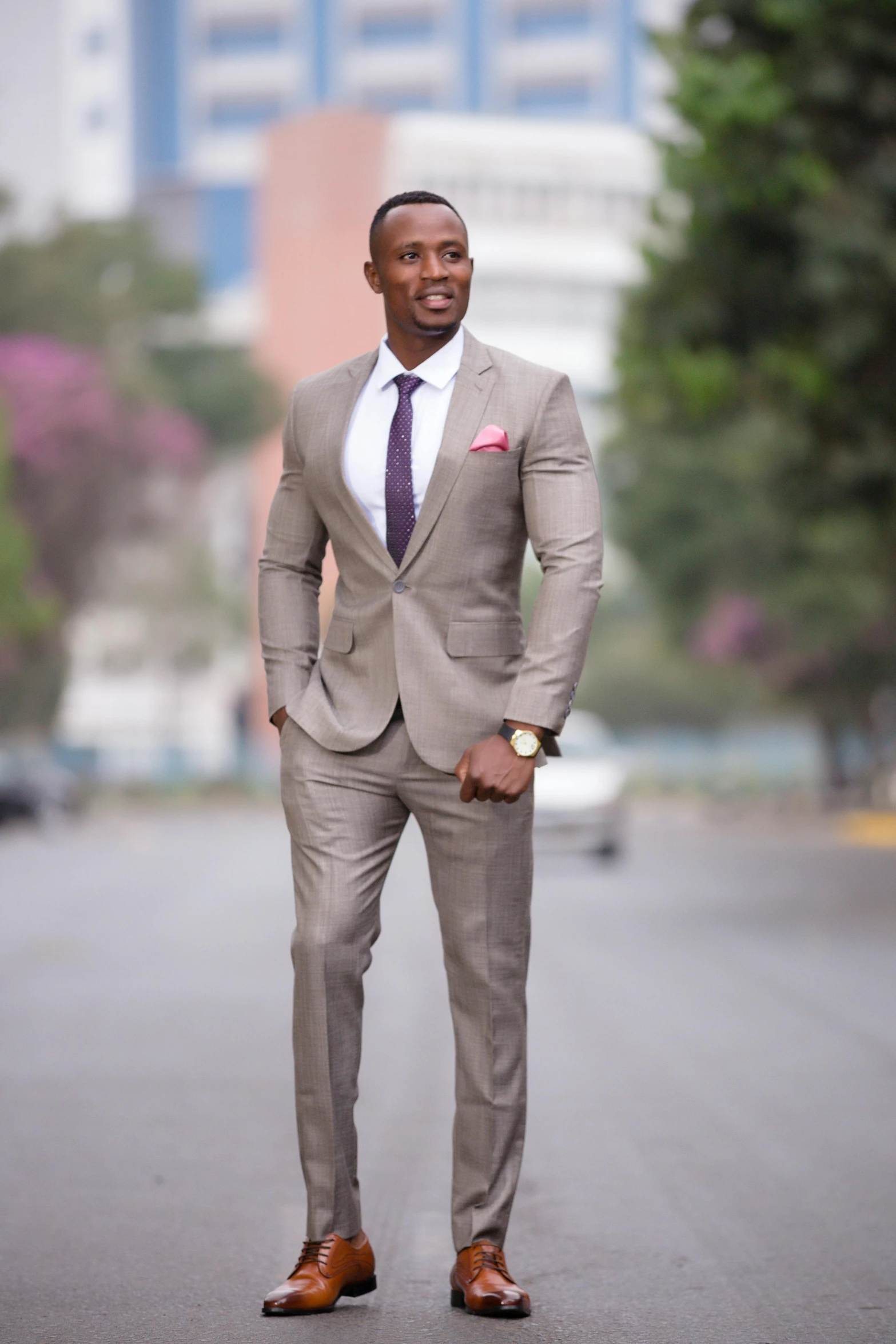 man in grey suit posing for picture on street