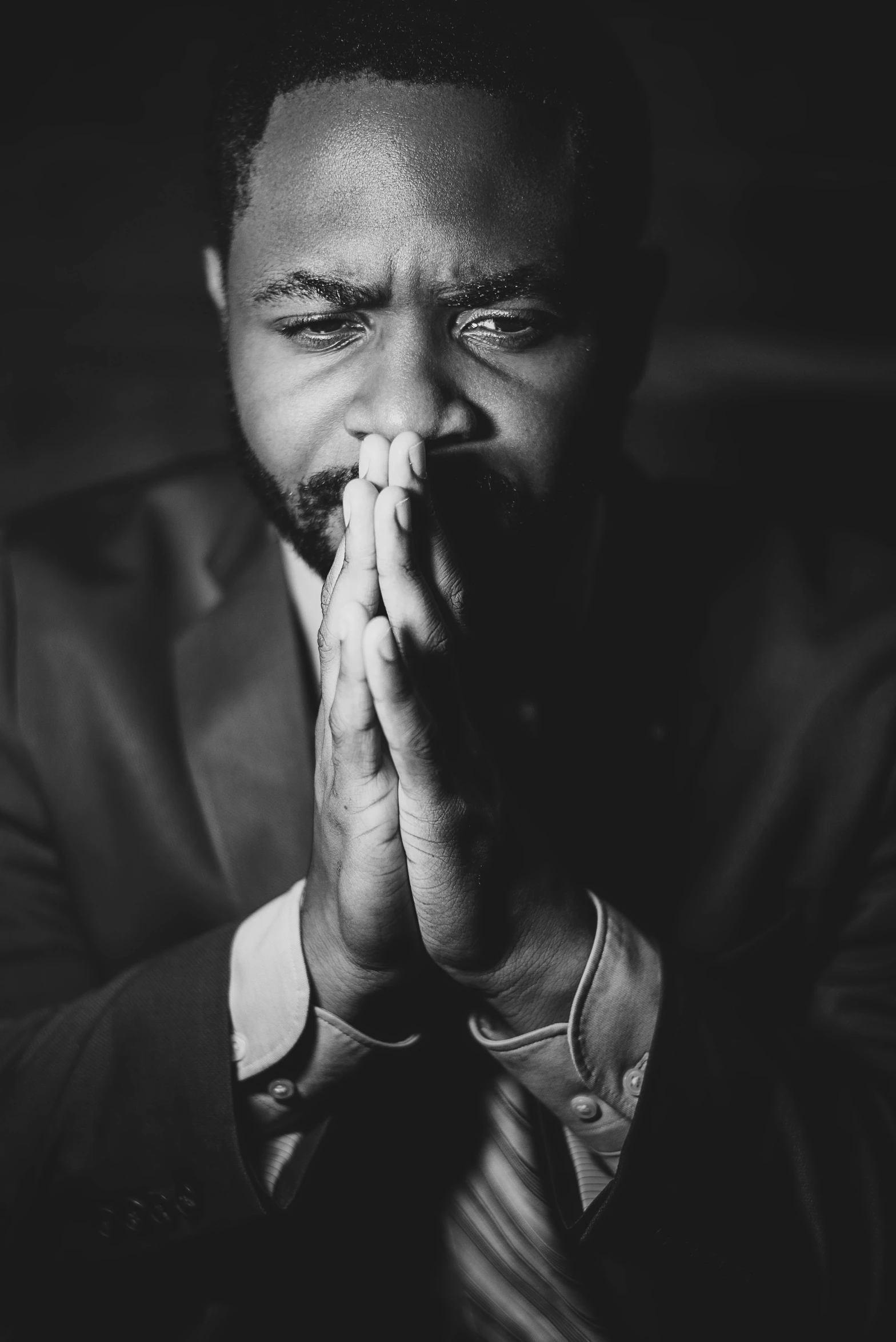 a man is standing and praying with his hands together