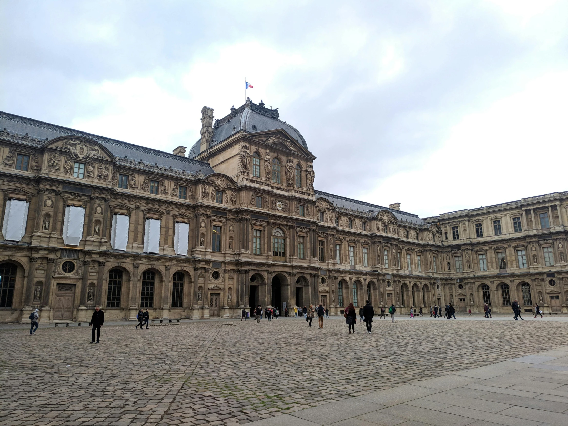 people walking around a large building near many other buildings