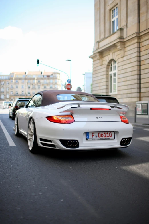 a white porsche cabriock is seen driving down a city street