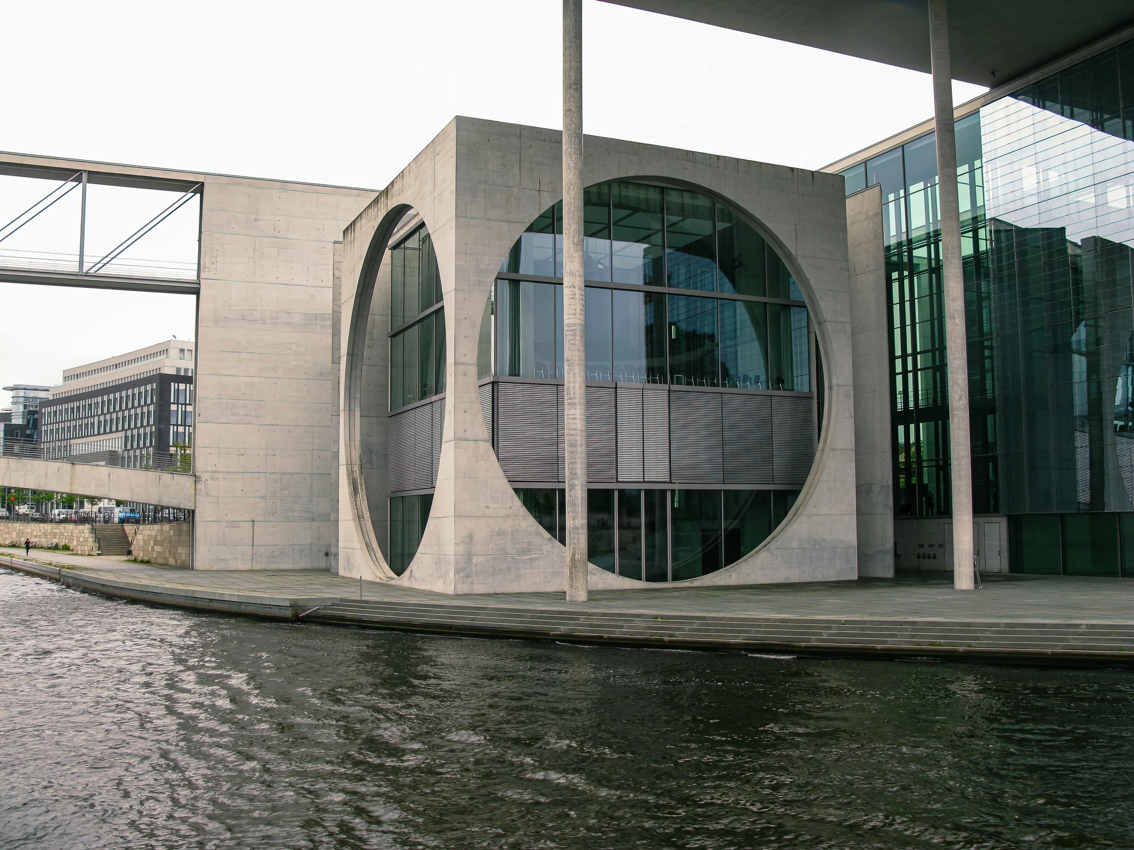 a building with some curved glass windows near water