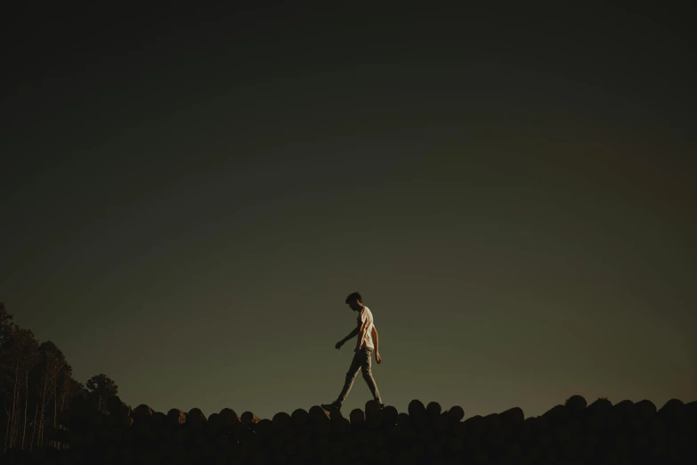 man walking on rocks while the moon is very low