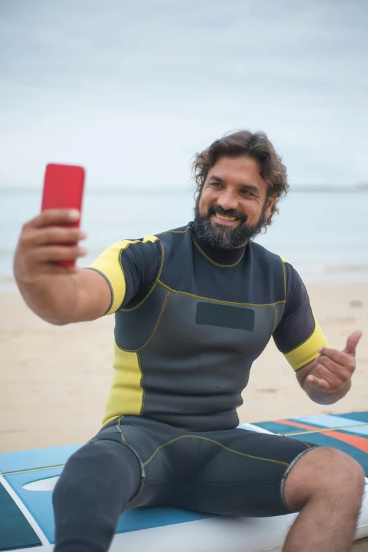 a man sitting on top of a surfboard holding a cell phone