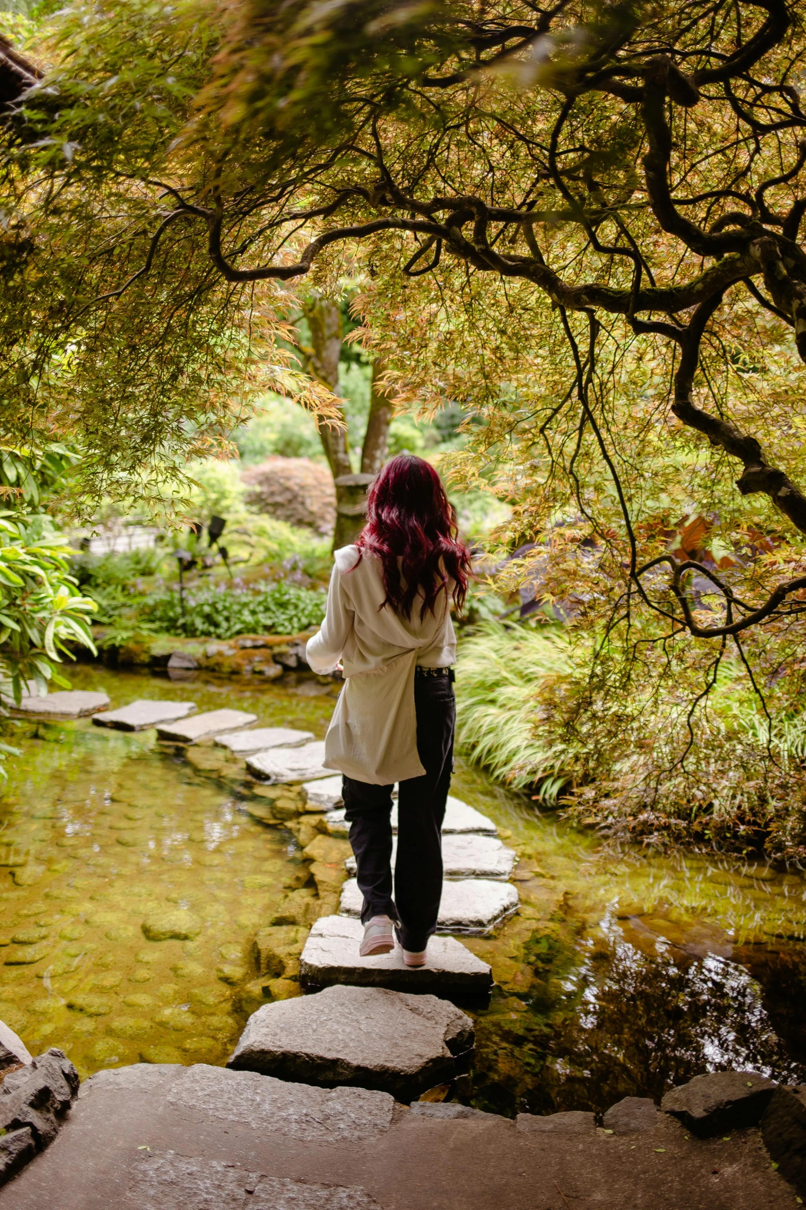 woman walking up a stone path toward a creek