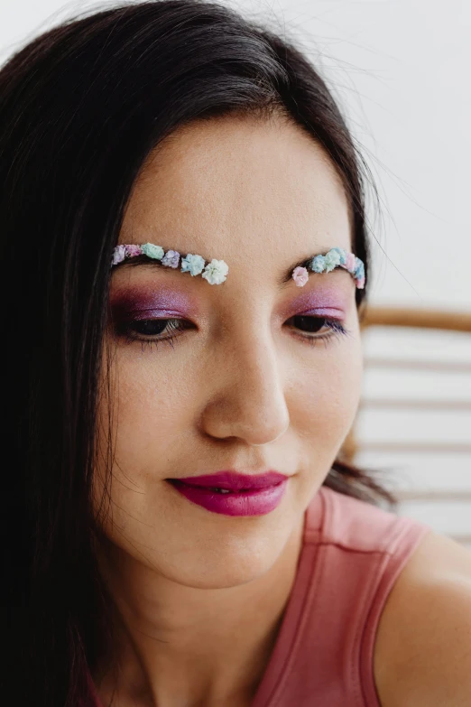 a girl with purple makeup wearing flowers on her eyes