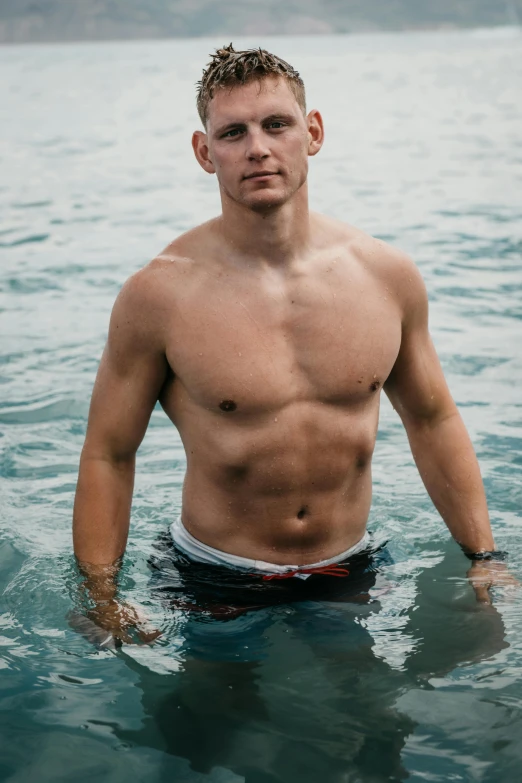 there is a male swimmer posing in the ocean