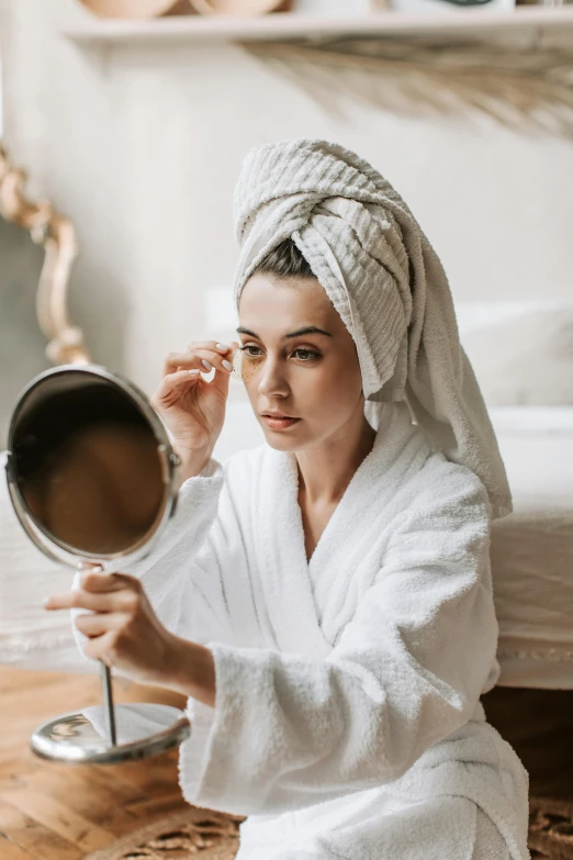 a woman is dressed in white, holding a mirror and looking into the camera