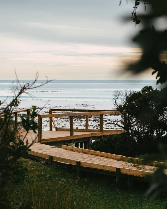 a bench on a wooden boardwalk by the beach