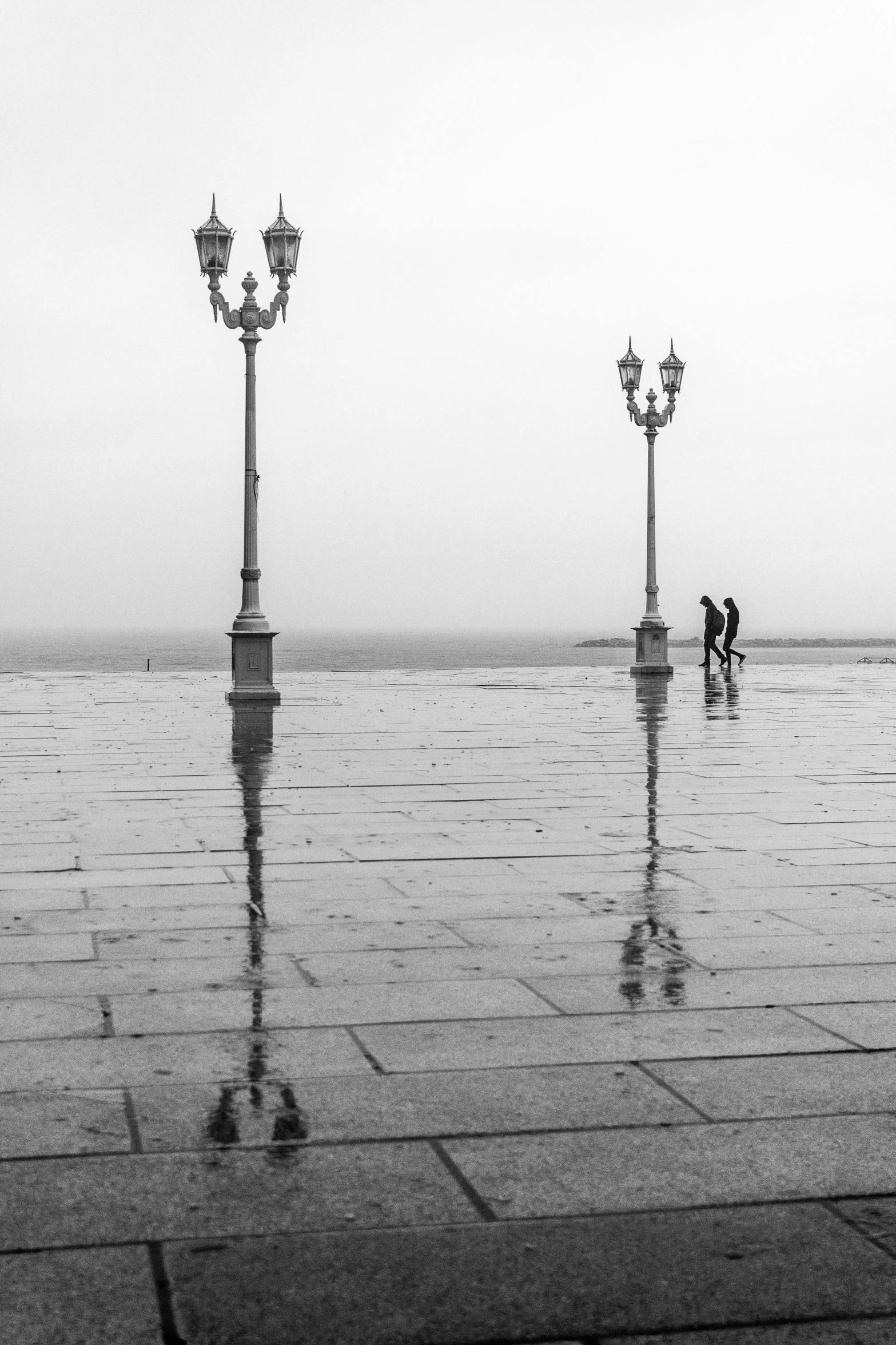 a man standing on top of a flooded surface next to tall street lamps