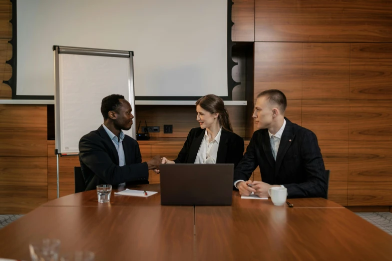 three business people sitting at a table discussing