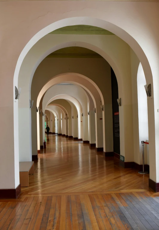 an arched walkway leads to a hall where visitors are seated
