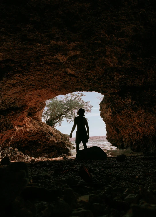 silhouetted man standing in the tunnel looking out at the ocean