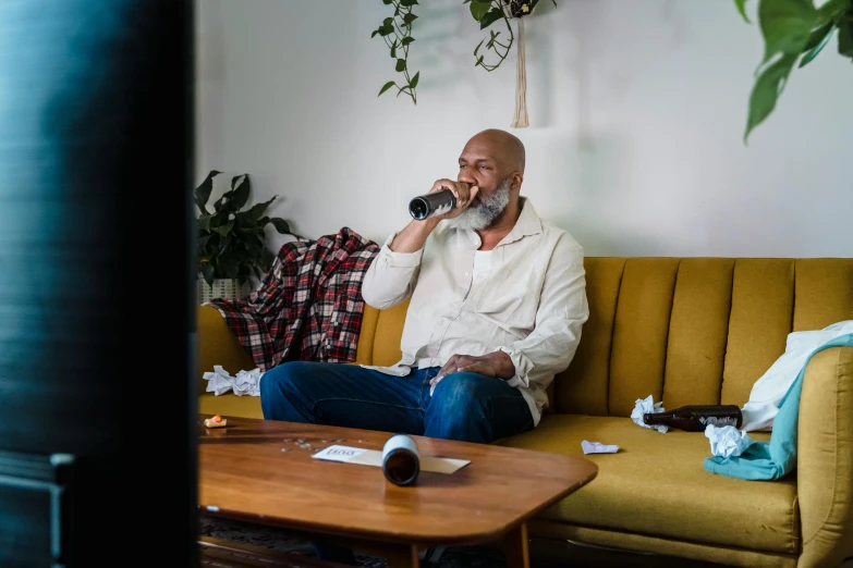 a man is drinking a glass on a couch